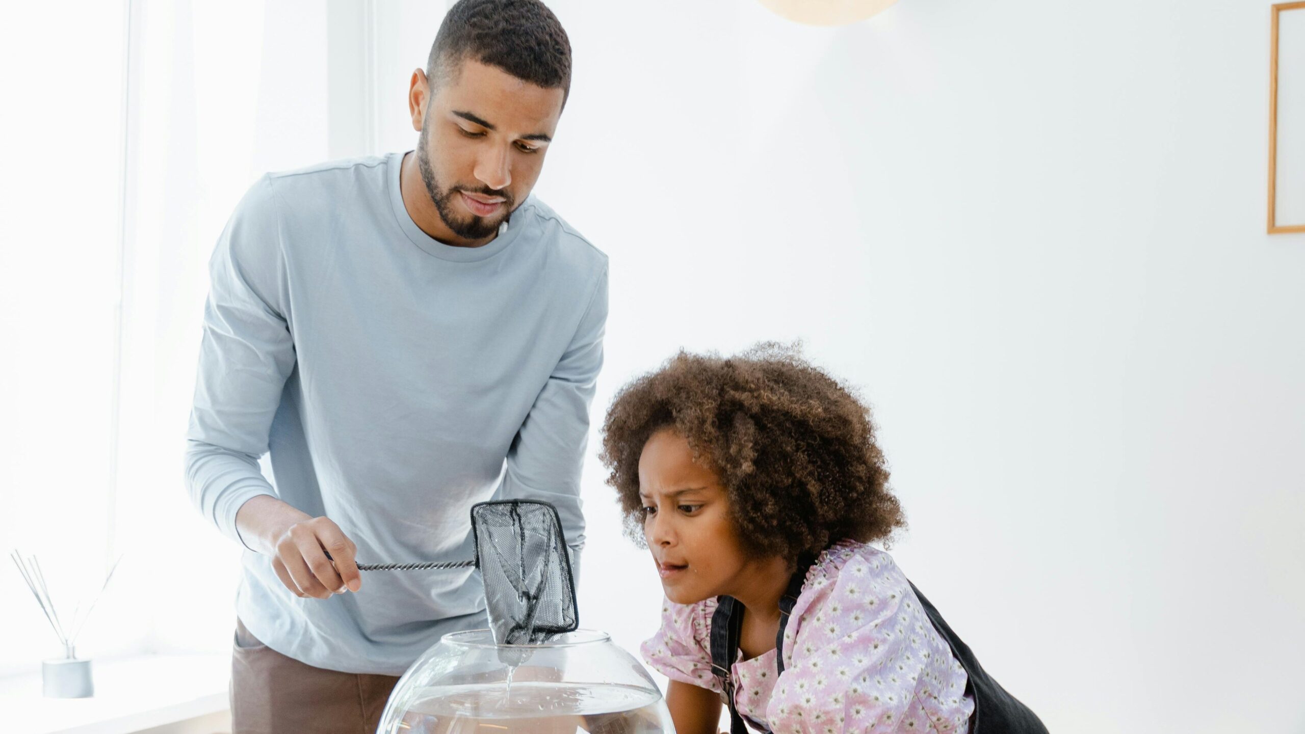 beginner aquarium setup A father and daughter bonding over aquarium maintenance at home, enjoying the hobby together.